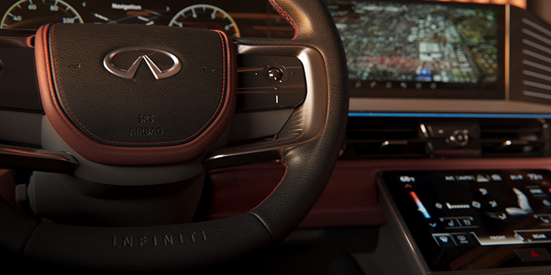 Close-up of a 2025 INFINITI QX80 steering wheel with a leather finish, featuring controls and a dashboard display in the background.