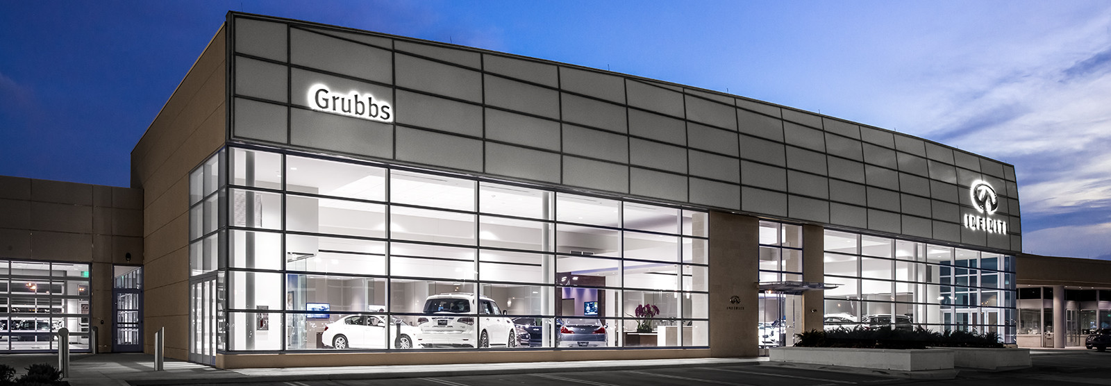 A car dealership building with large glass windows, showing cars inside, and a sign that says 'Grubbs'.
