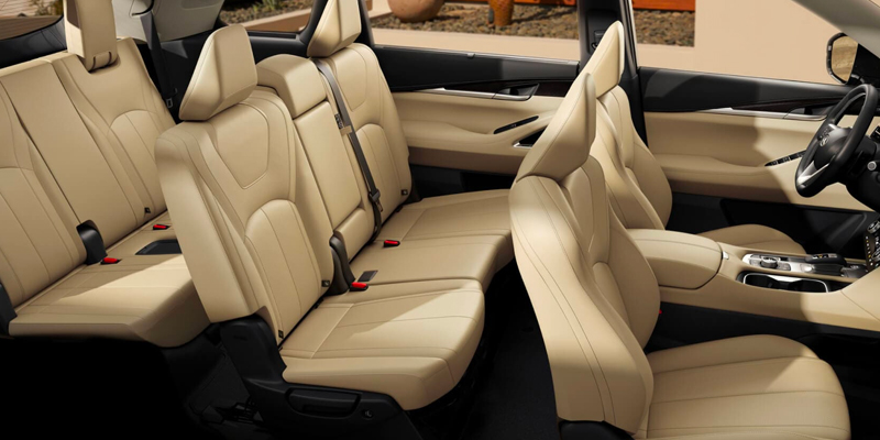 Spacious interior of a 2025 INFINITI QX60 with beige leather seats, featuring seat belts and a sleek design.