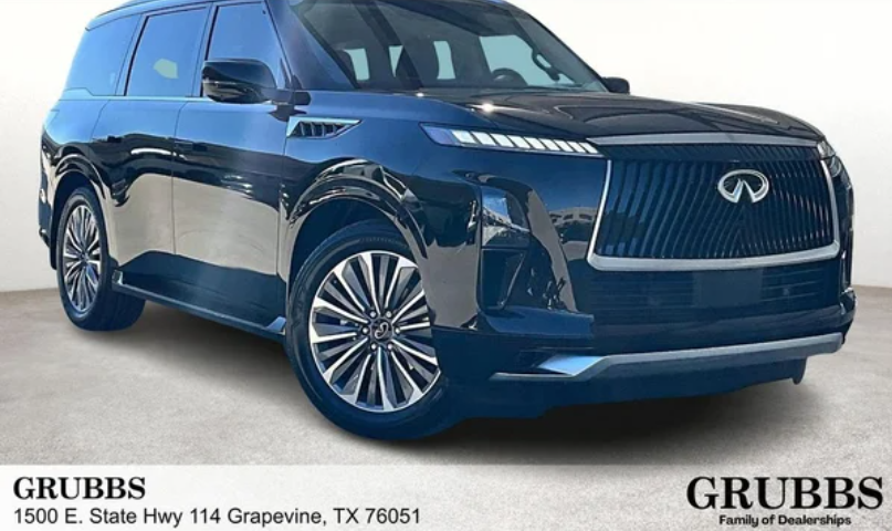 A dark blue luxury 2026 INFINITI QX80 Luxe SUV with a sleek grille parked in front of a dealership.